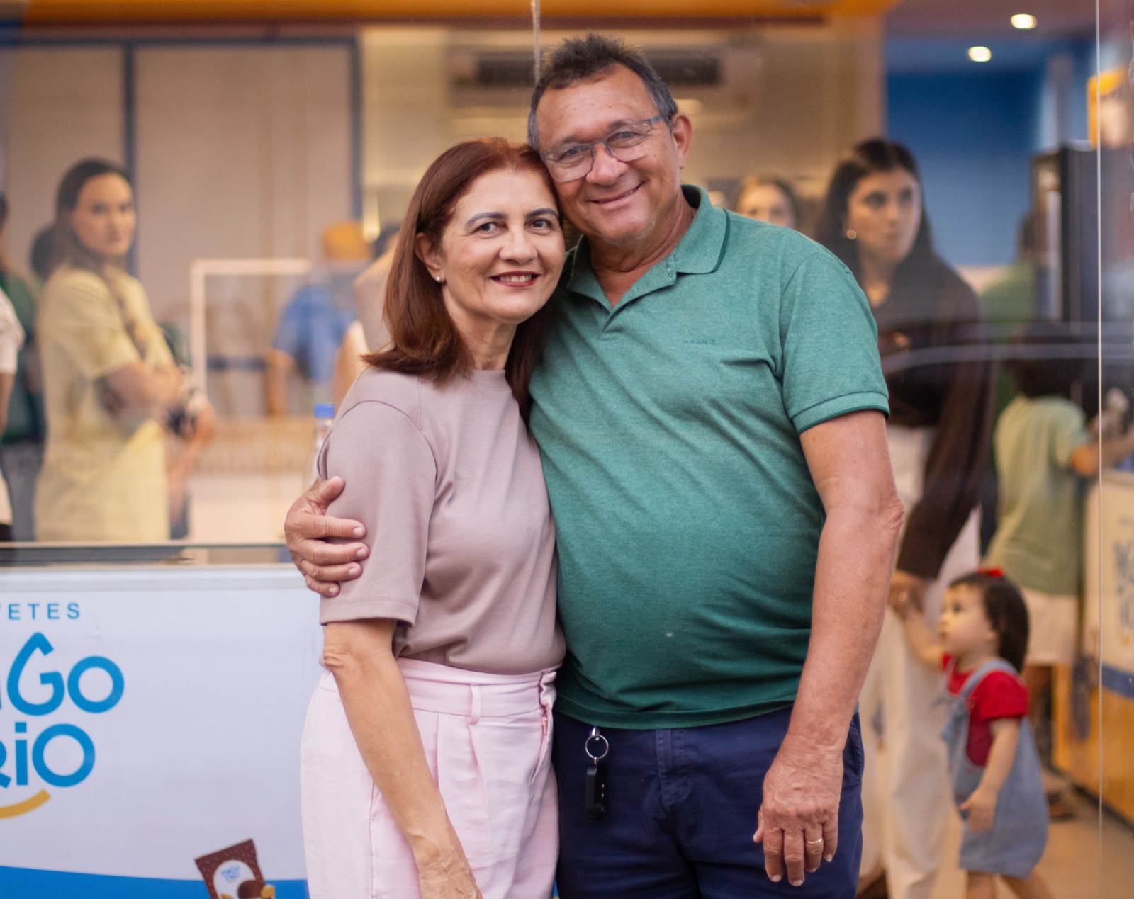 Casal de clientes abraçados e sorrindo em frente ao freezer Pingo Frio